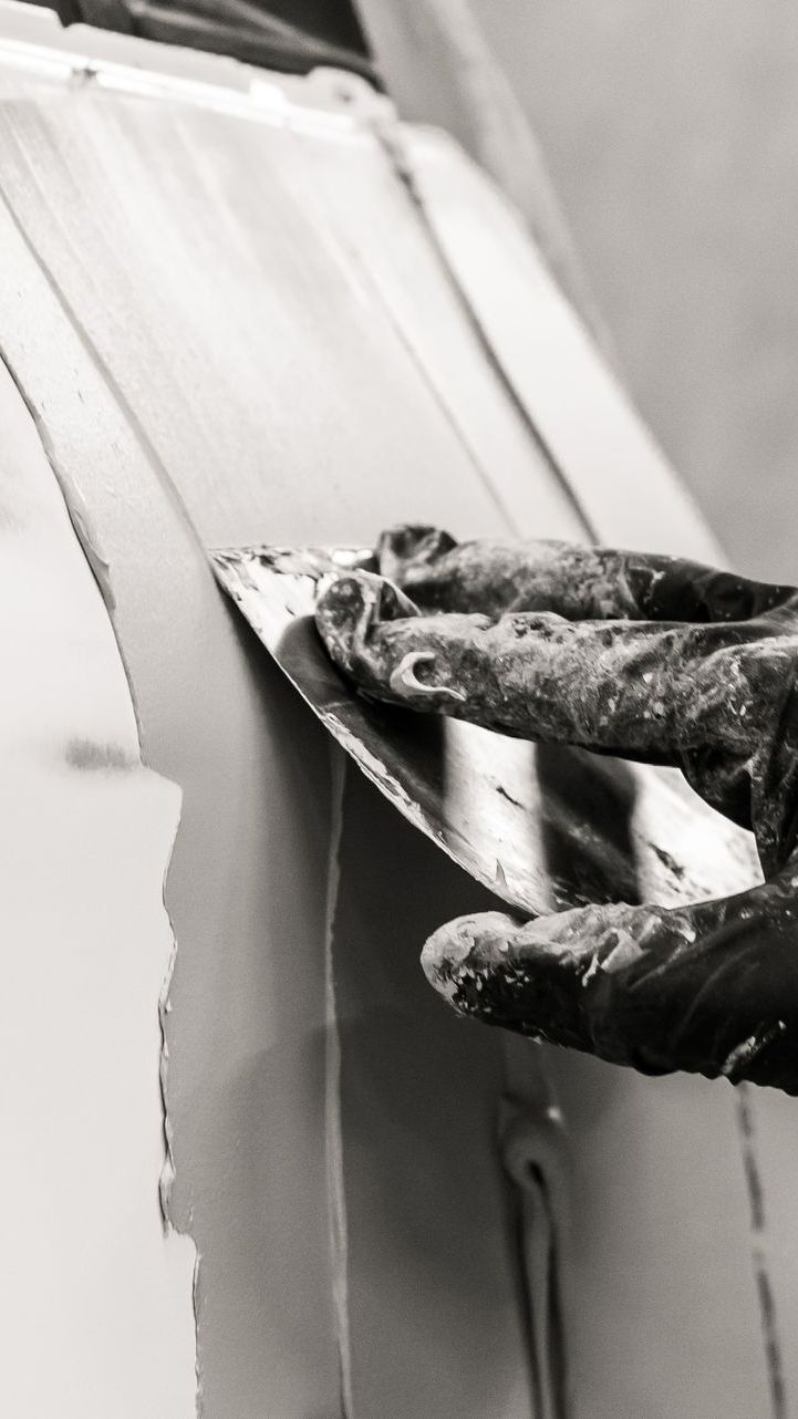 Une main passant du mastic sur une carrosserie