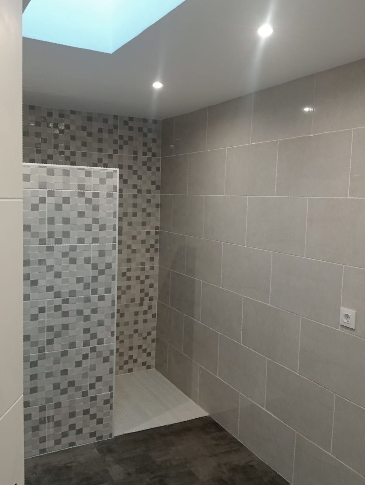 Un baño con ducha a ras de suelo y tragaluz.