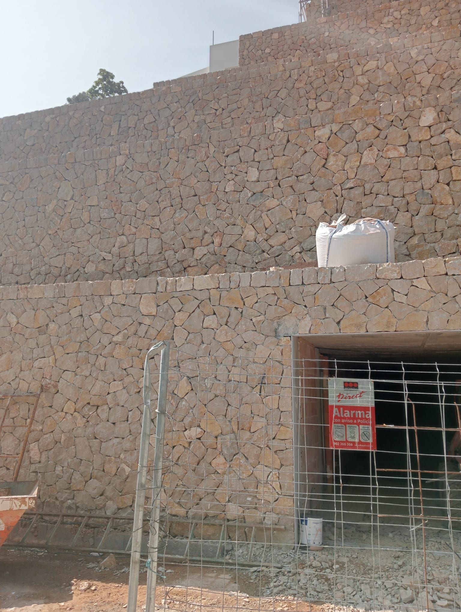 Un gran muro de piedra con una valla alrededor.