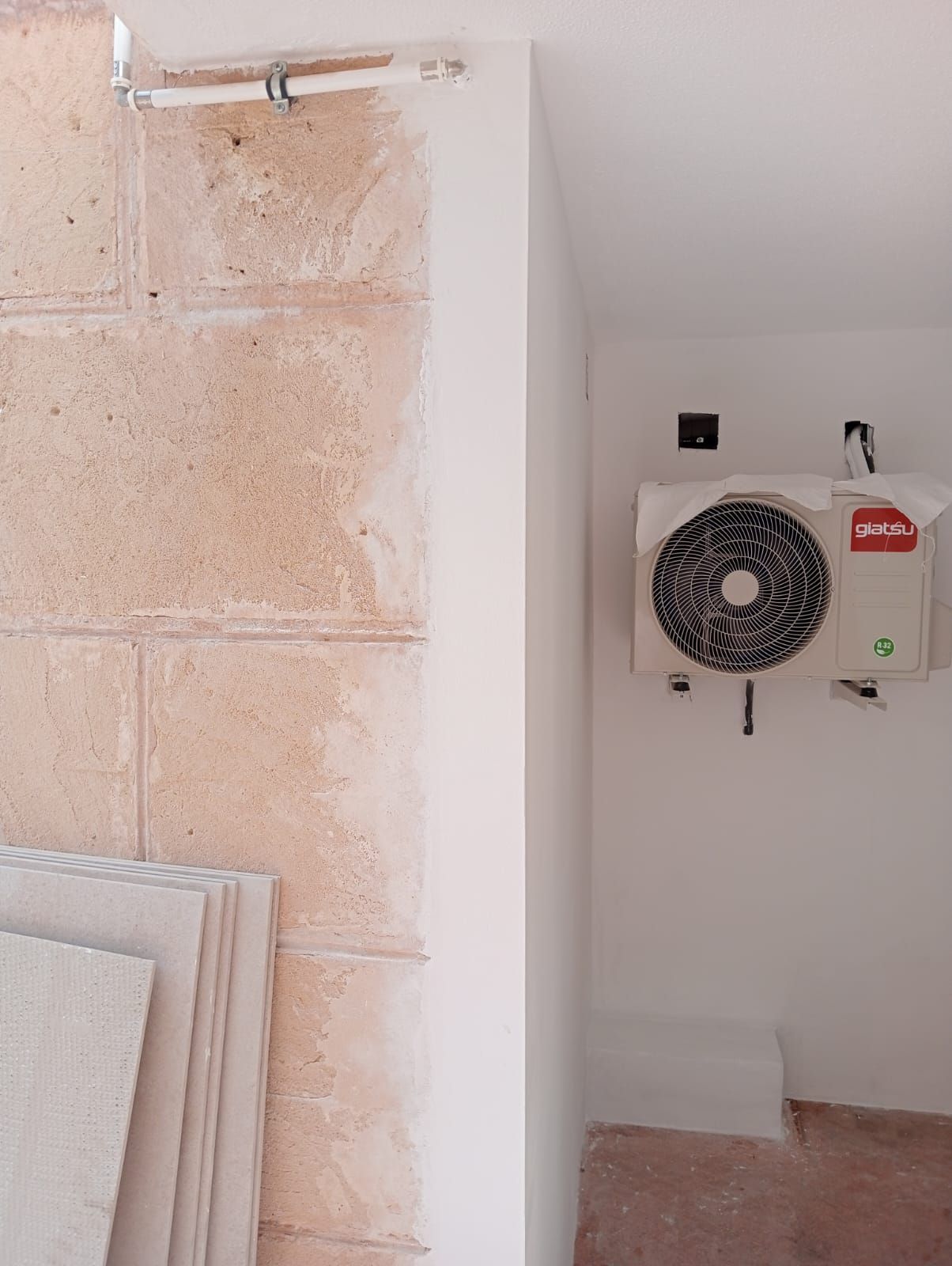 Una habitación con una pared de ladrillos y un ventilador en la pared.