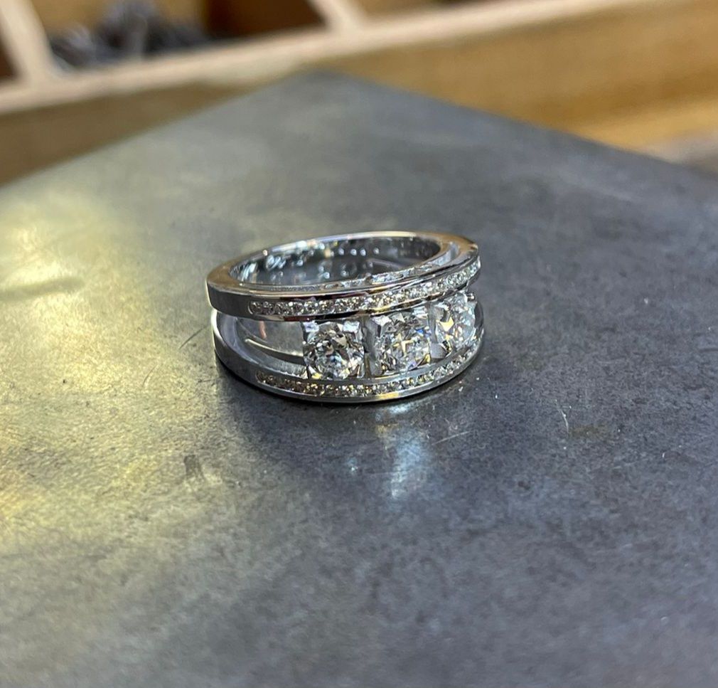 Bague en or blanc avec trois diamants centrés et sertie de diamants en rail