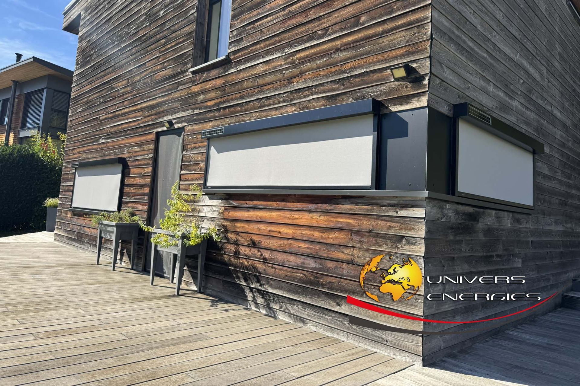 Bâtiment en bois avec trois auvents extérieurs. Des jardinières avec des plantes vertes sont disposées en dessous.