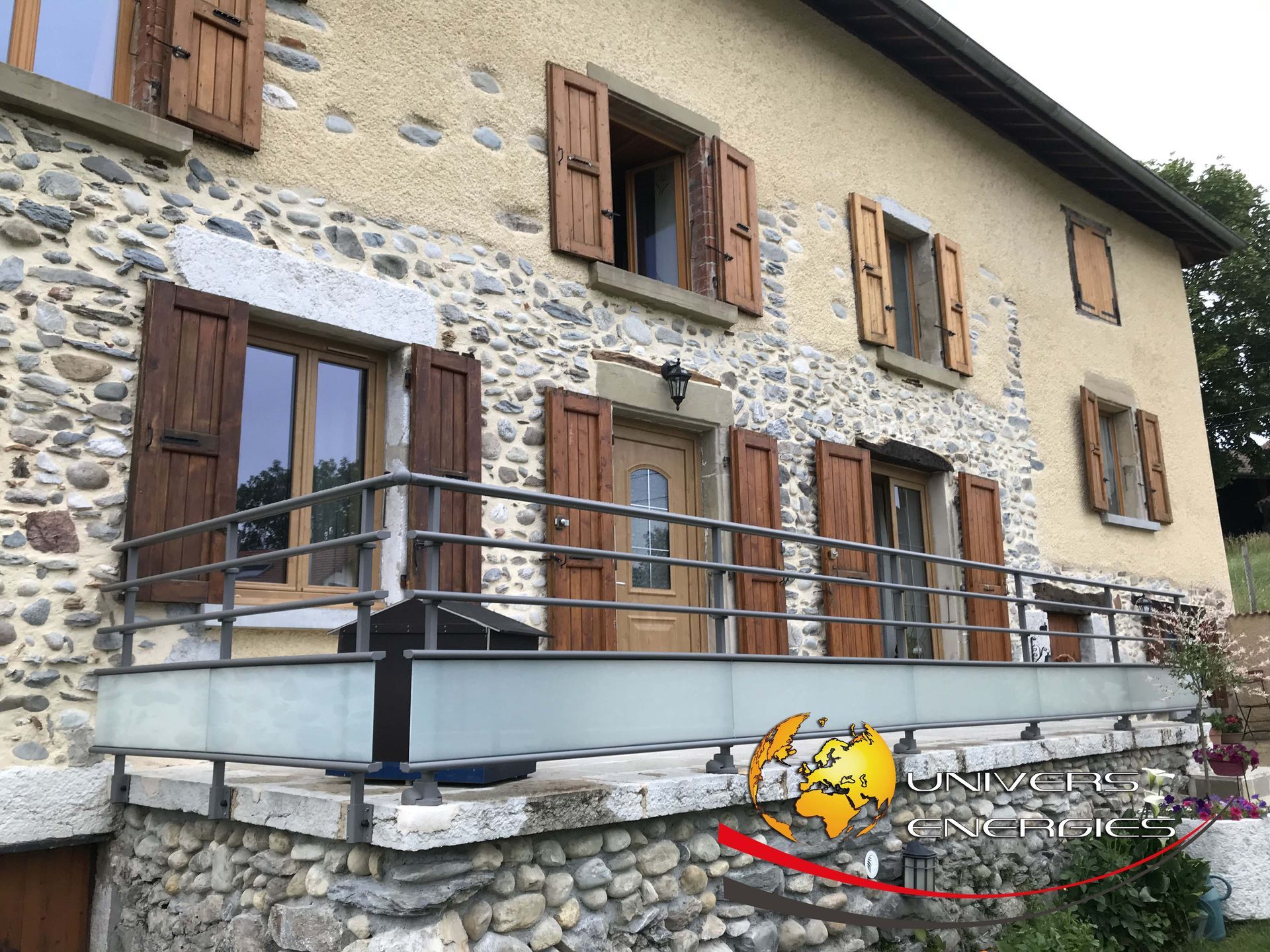Maison en pierre de deux étages avec balcon et volets en bois, située à l'extérieur.