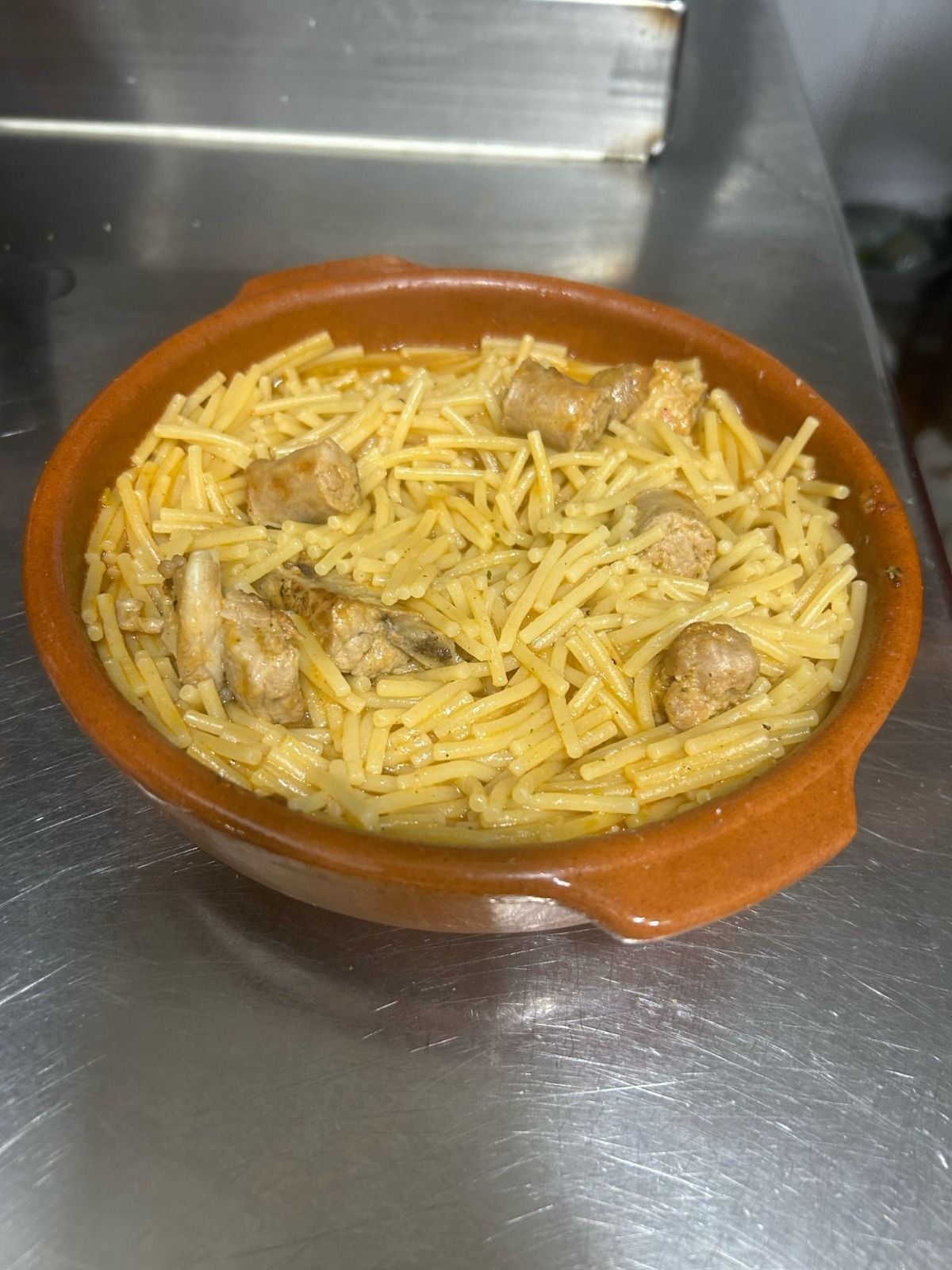 Un plato de fideos y carne está sobre una mesa.