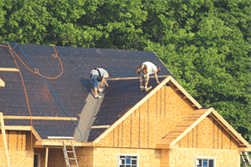 Dos hombres están trabajando en el tejado de una casa en construcción.