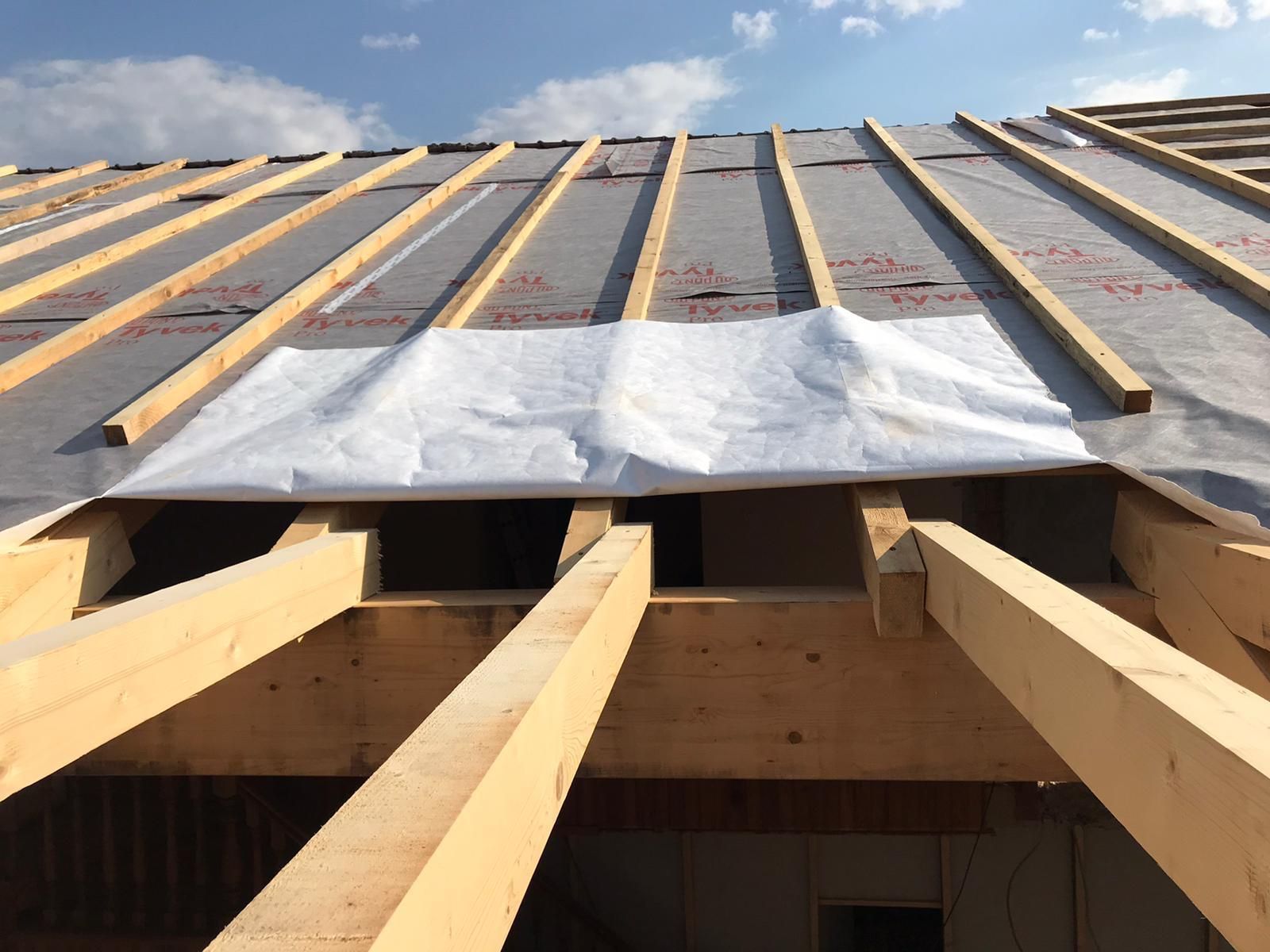 Holzdachkonstruktion mit grauer Membran und weißem Stoff.