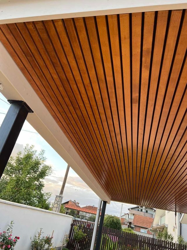 Holzlattendecke auf einer Veranda, mit weißer Verkleidung und schwarzem Stützpfosten.