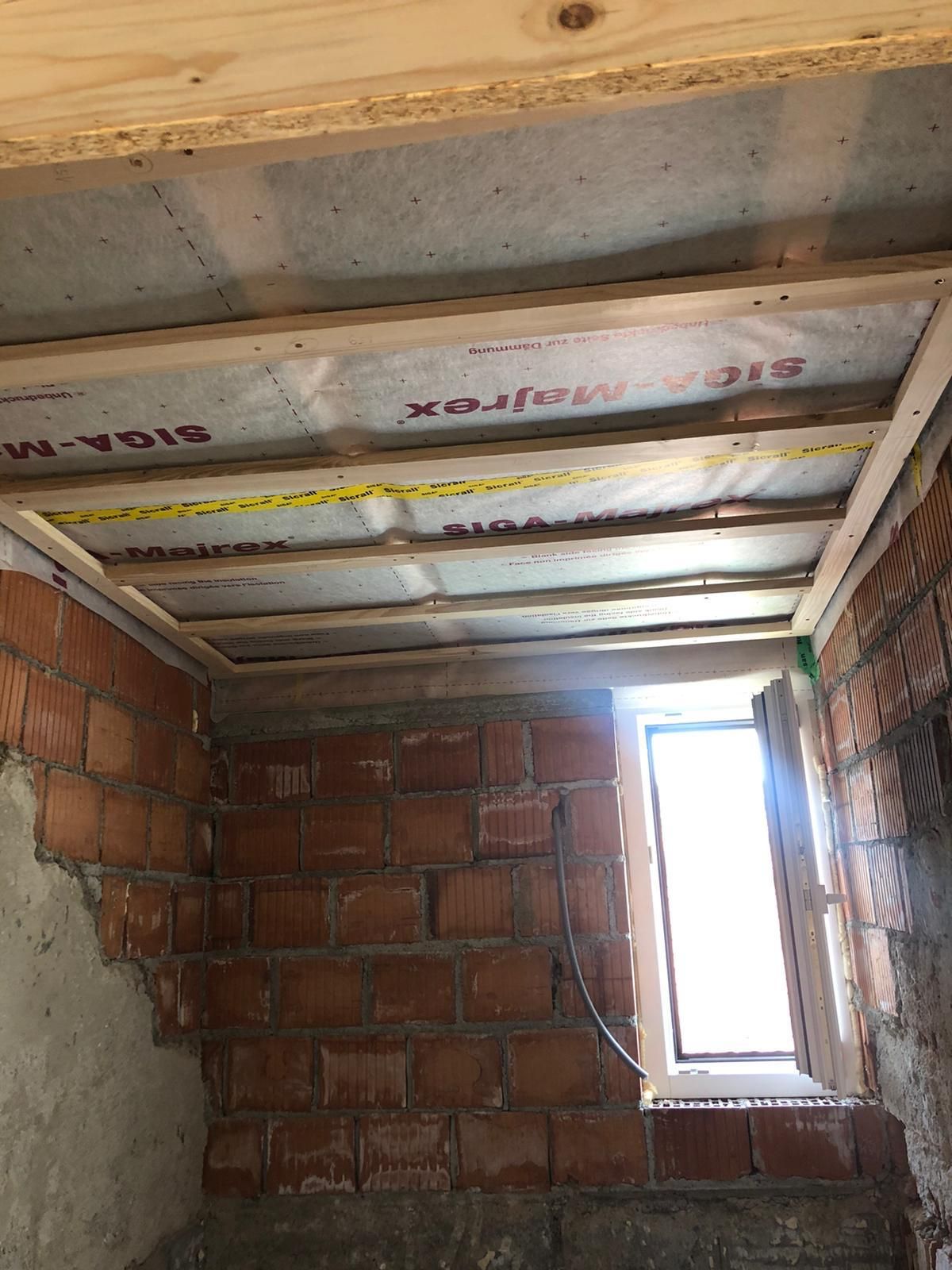 Innenausbau: Ziegelwände, Holzdeckenrahmen mit Dampfsperre und Fenster.