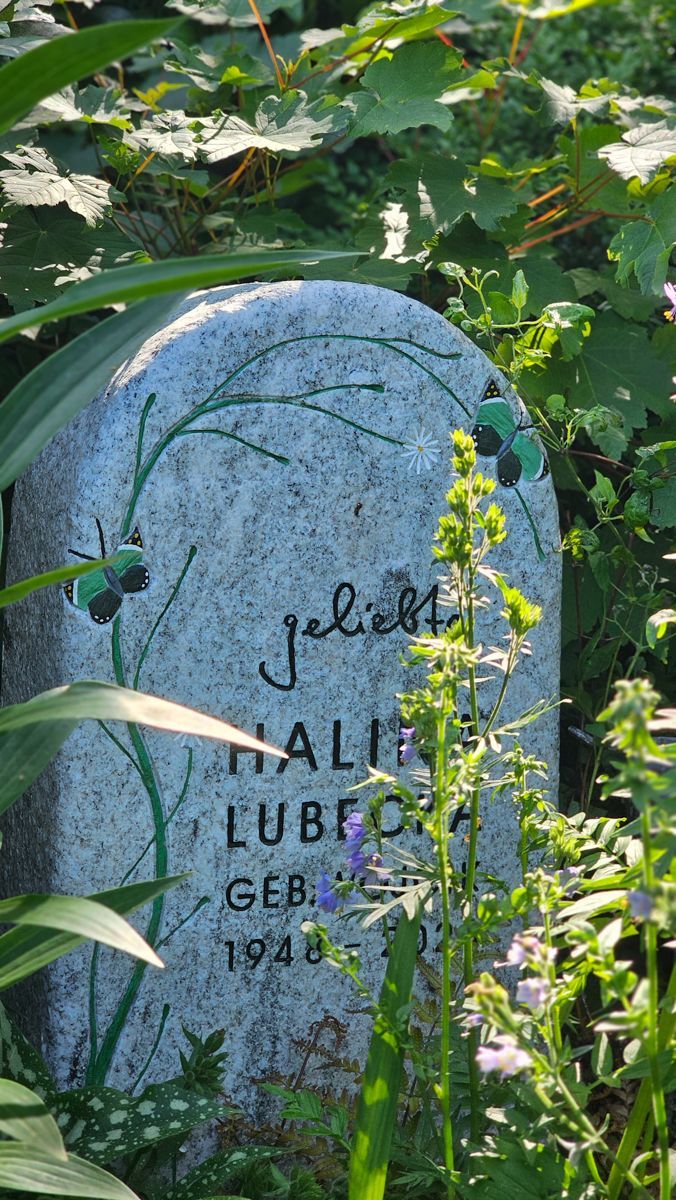 Grabstein mit aufgemalten grünen Ranken und dem Wort „geliebt“.
