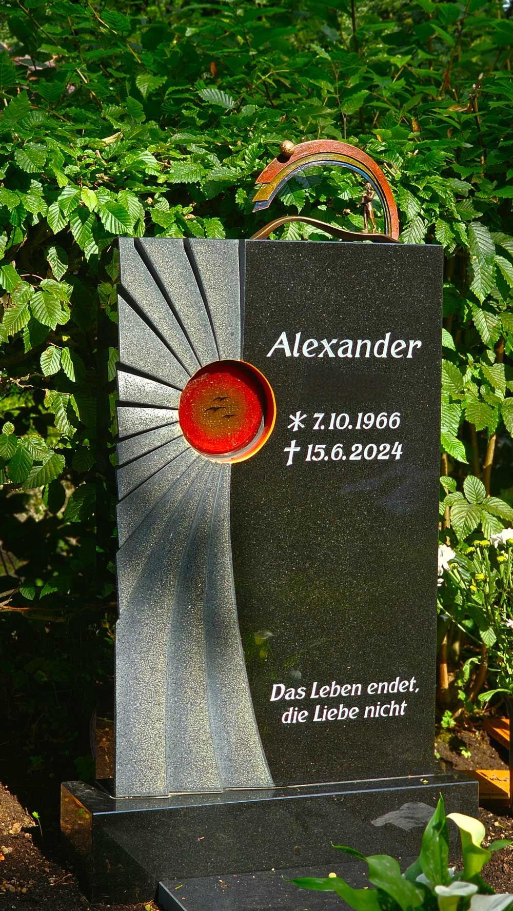 Schwarzer Granitgrabstein mit Sonnenmotiv und dem Namen
