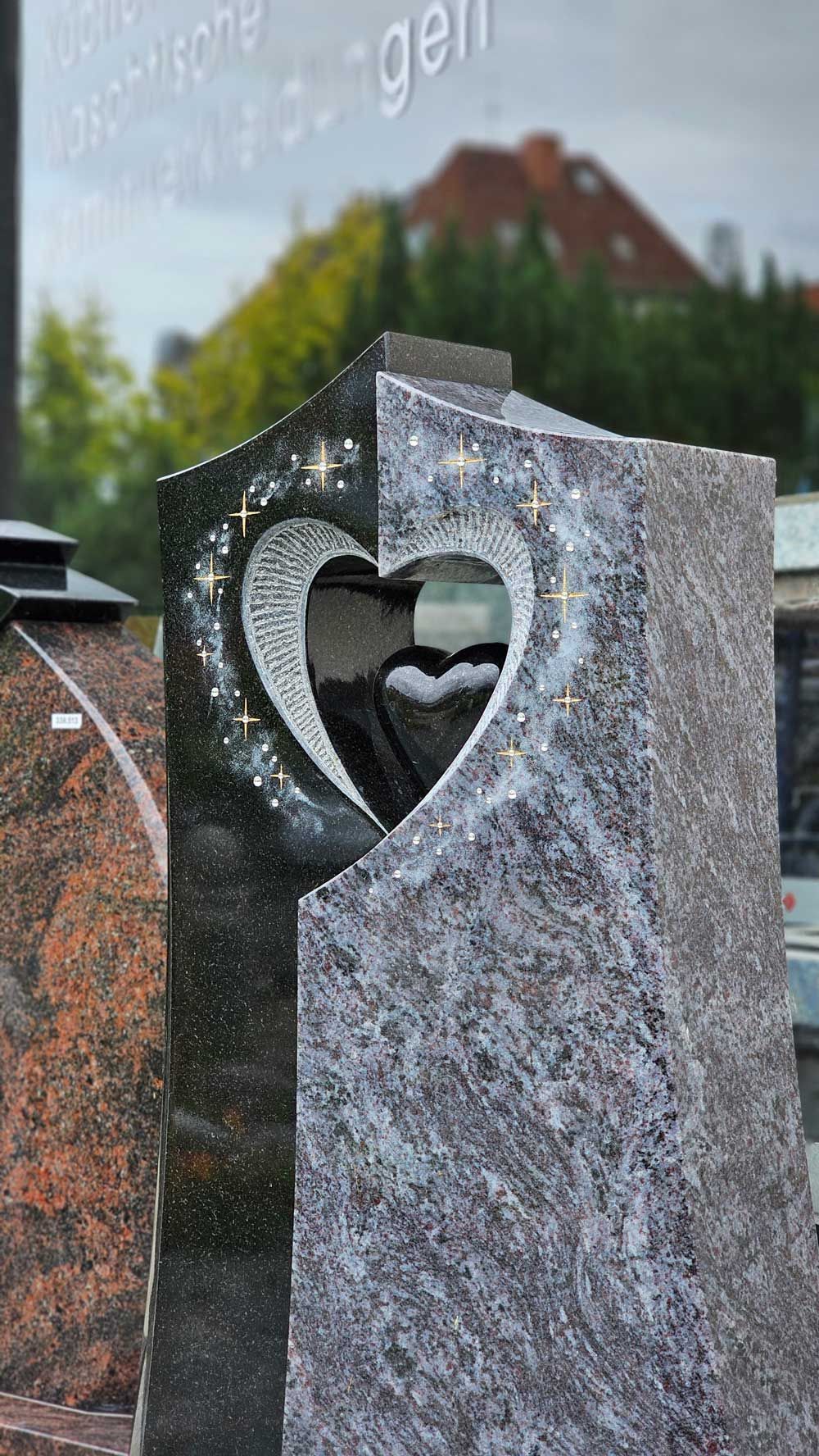 Granitgrabstein mit herzförmigem Ausschnitt, dunkel- und hellgraue Farbtöne.