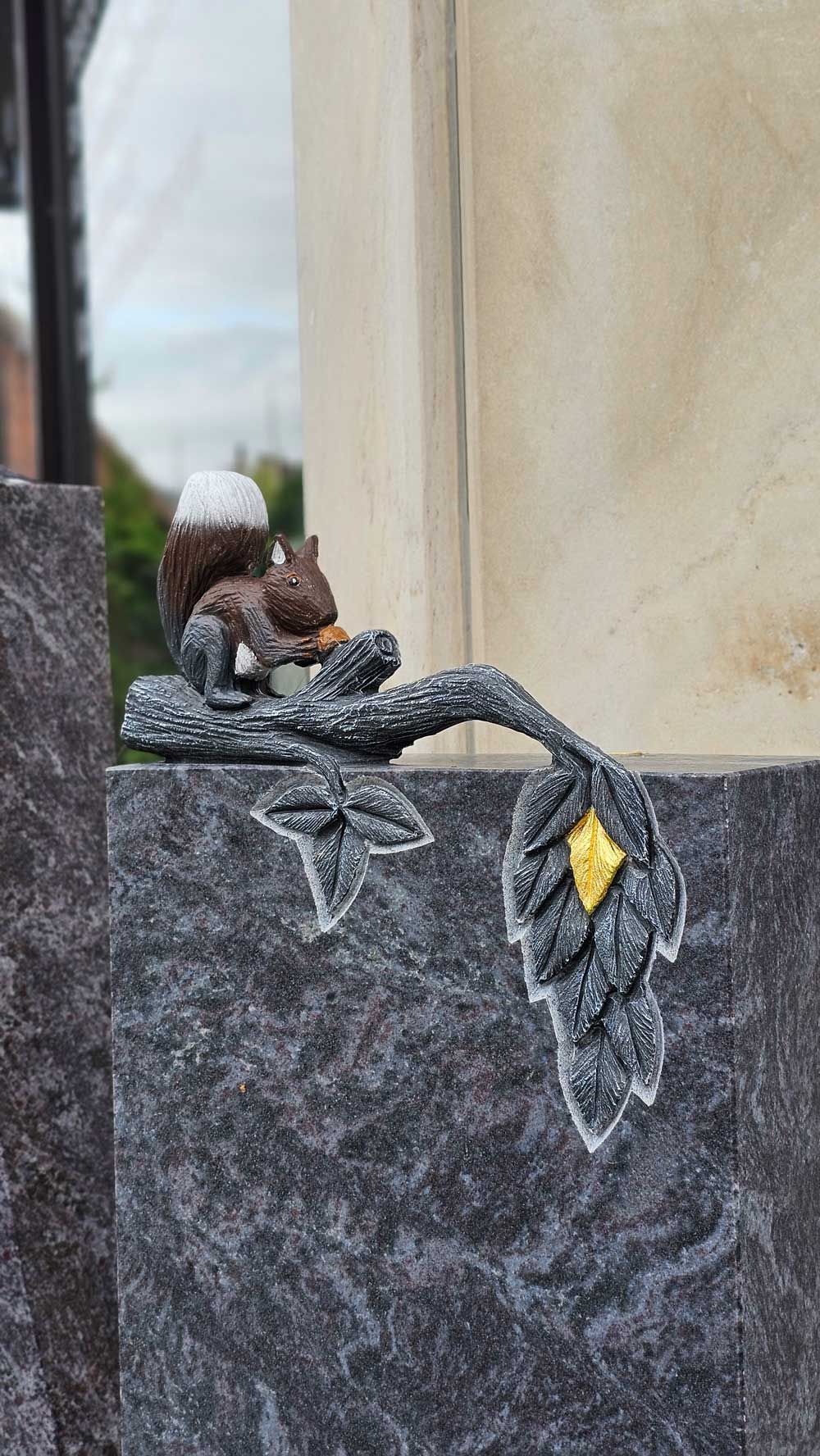Eichhörnchenskulptur auf einem dunkelgrauen Granitdenkmal mit Blattdetail und goldenen Akzenten.