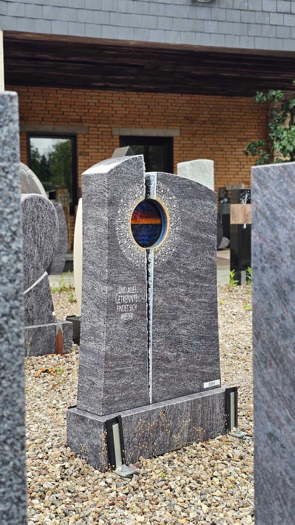 Grauer Granitgrabstein mit kreisförmigem Ausschnitt, im Freien stehend.