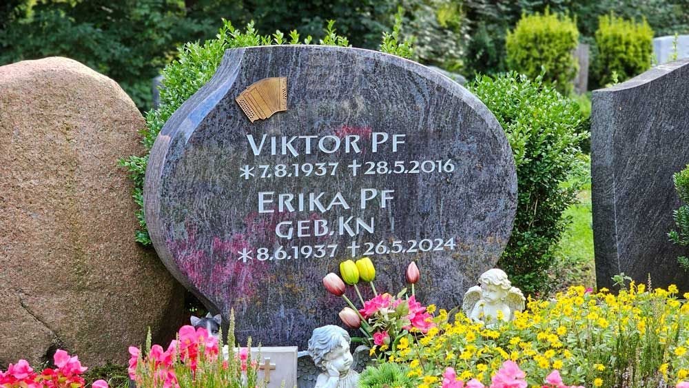 Schwarzer Granitgrabstein mit einer kreisförmigen Abbildung eines Gebäudes und der Aufschrift „St. Petersburg“.