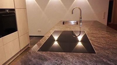 Moderne Kücheninsel mit eingebauter Spüle, Wasserhahn und integrierter Beleuchtung.