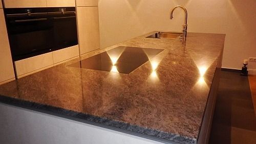 Kücheninsel mit Granitarbeitsplatte, Spüle, Wasserhahn und Einbauleuchten.