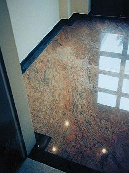 Polierter Granitboden mit dunklem Rand, der das Licht der darüber liegenden Fenster reflektiert.