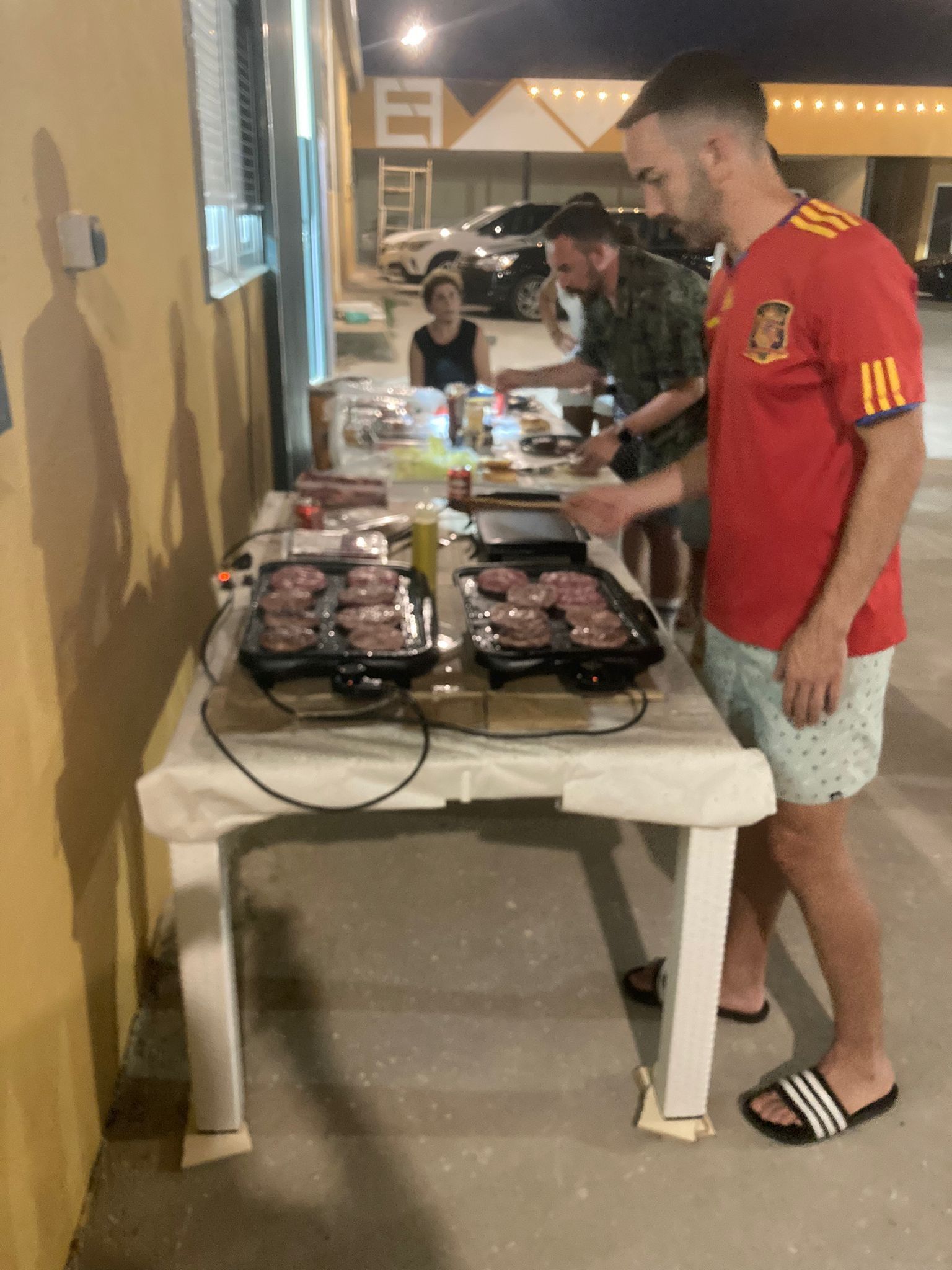 Un hombre con una camisa roja está parado frente a una mesa con comida.