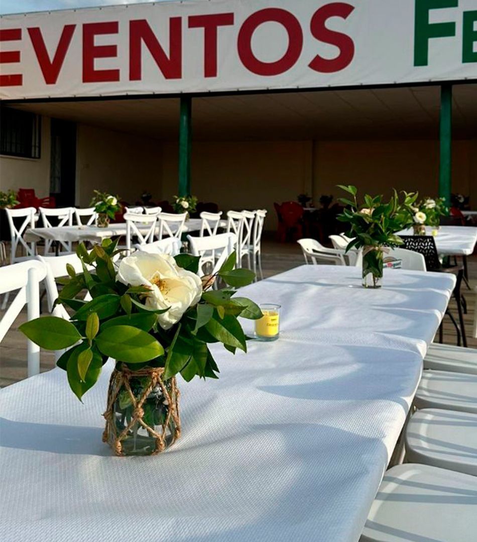 Una mesa con flores delante de un cartel que dice eventos fe