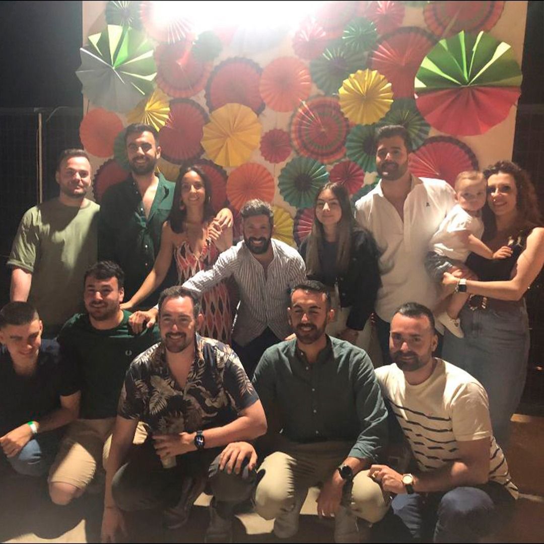 Un grupo de personas posando para una foto frente a una pared de abanicos de papel.