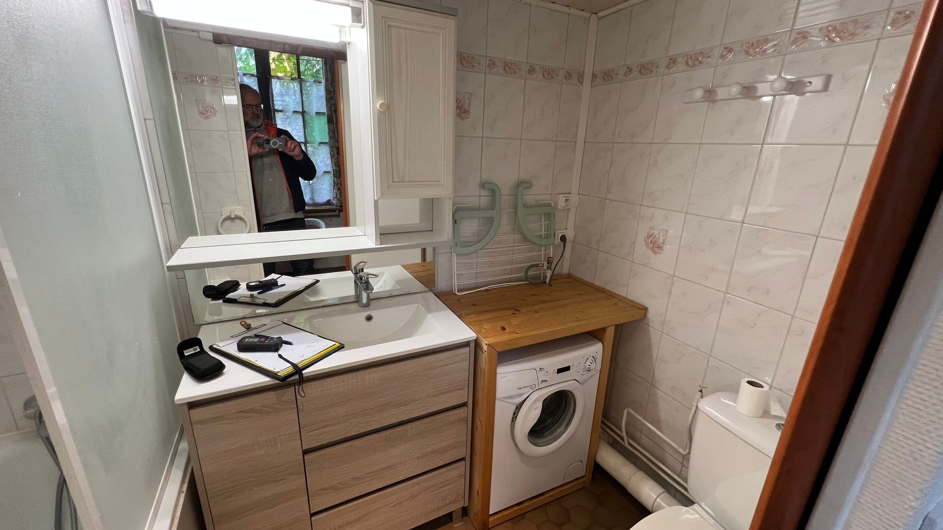 Petite salle de bain avec lavabo, meuble vasque, machine à laver et toilettes.