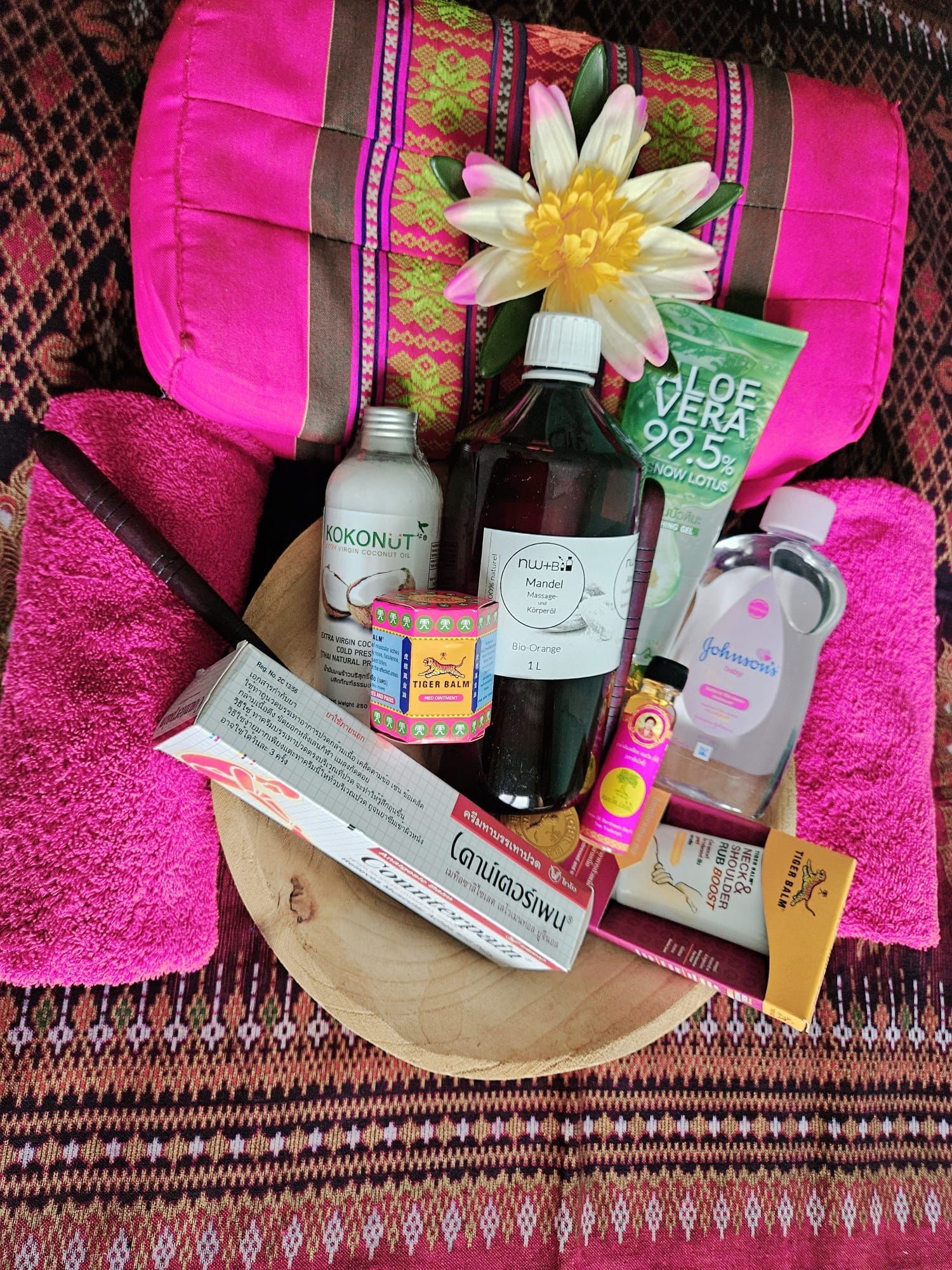 Rosa Spa-Produkte: Handtücher, Kissen, Toilettenartikel und Holzschale.