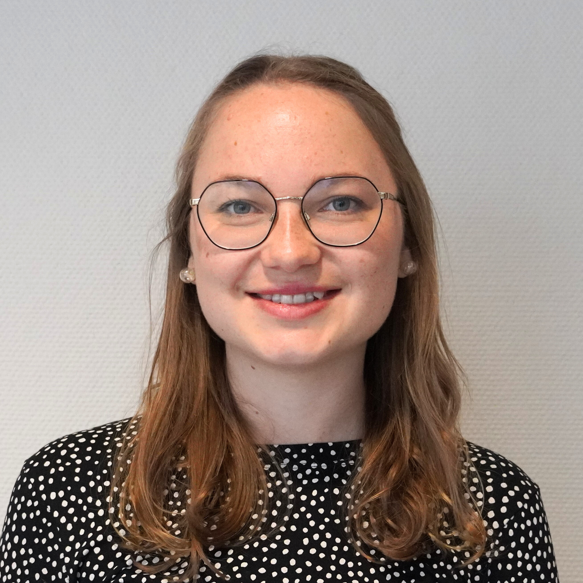 Eine Frau mit Brille und schwarz weißem Hemd lächelt in die Kamera.