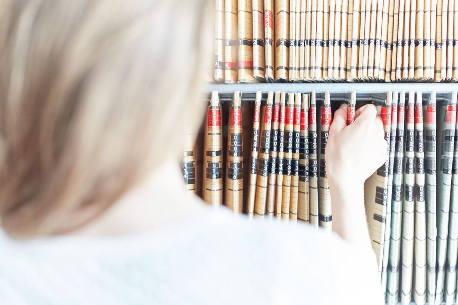 Eine Frau nimmt ein Buch aus einem Bücherregal in einer Bibliothek.