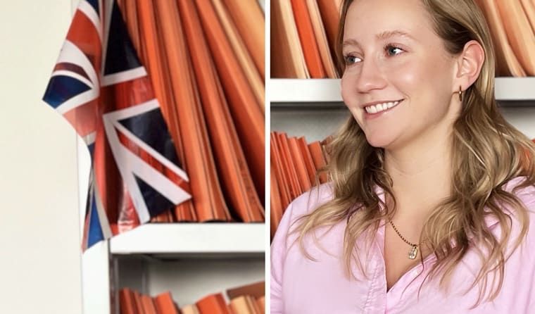 Eine Frau steht vor einem Bücherregal mit einer britischen Flagge im Hintergrund.