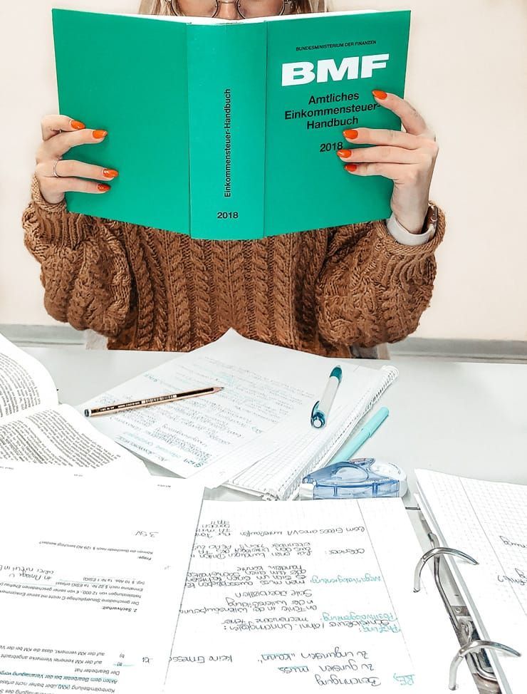 Eine frau sitzt an einem schreibtisch und liest ein buch mit dem titel bmf.