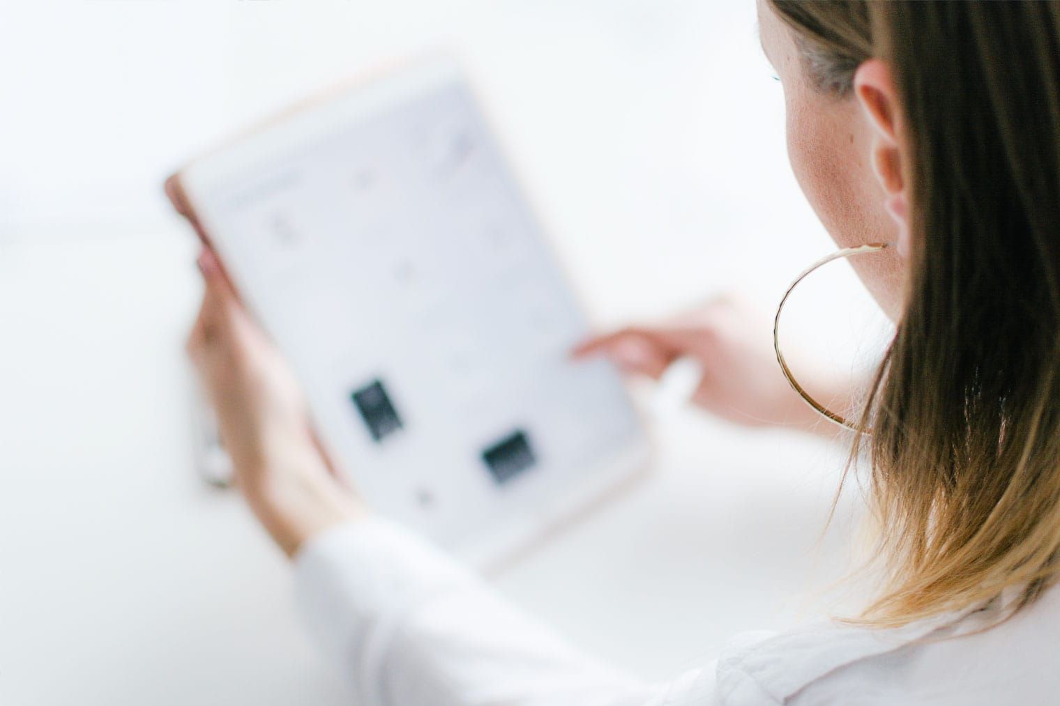 Eine Frau mit Creolen benutzt einen Tablet-Computer.
