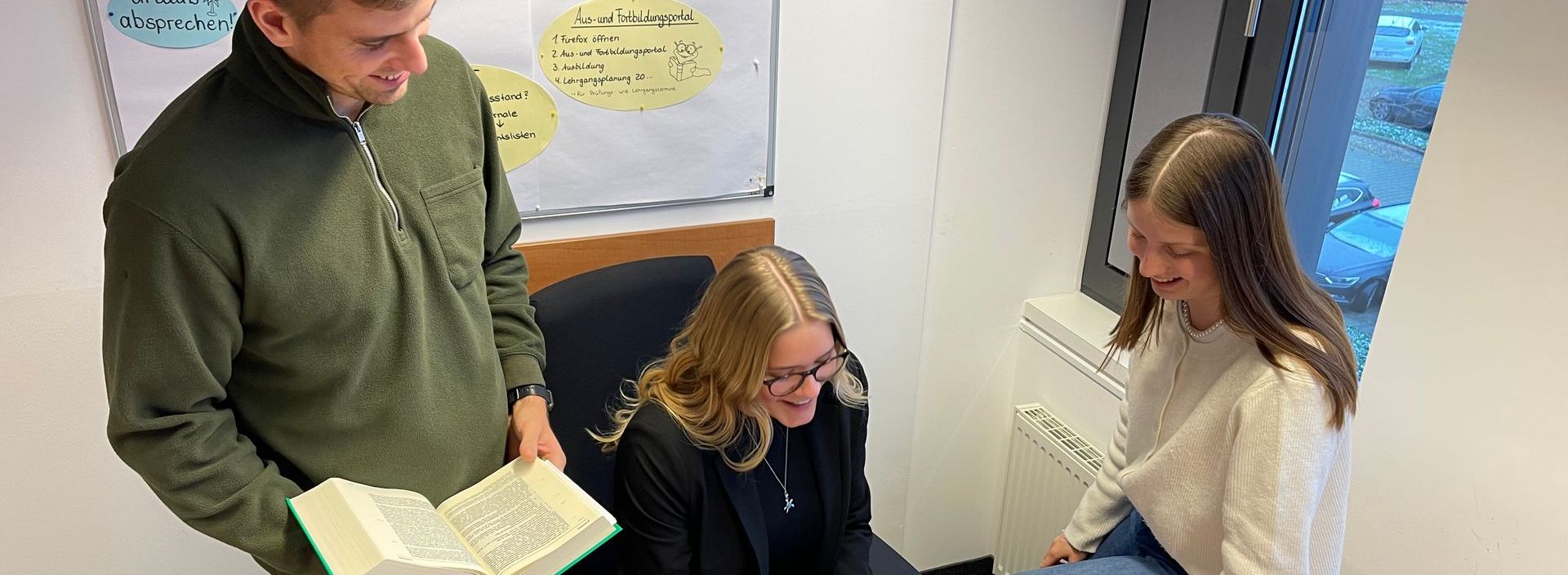 Eine Frau steht vor einem Bücherregal mit einer britischen Flagge im Hintergrund.