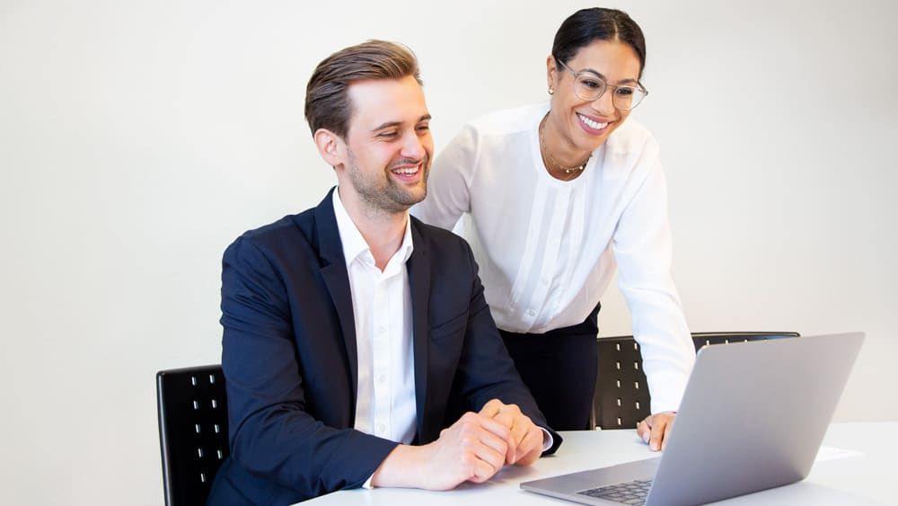 Ein Mann und eine Frau schauen sich einen Laptop an.
