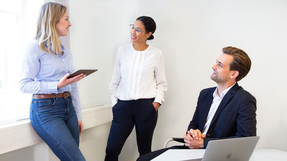 Eine Gruppe von Leuten steht um einen Tisch herum und unterhält sich miteinander.