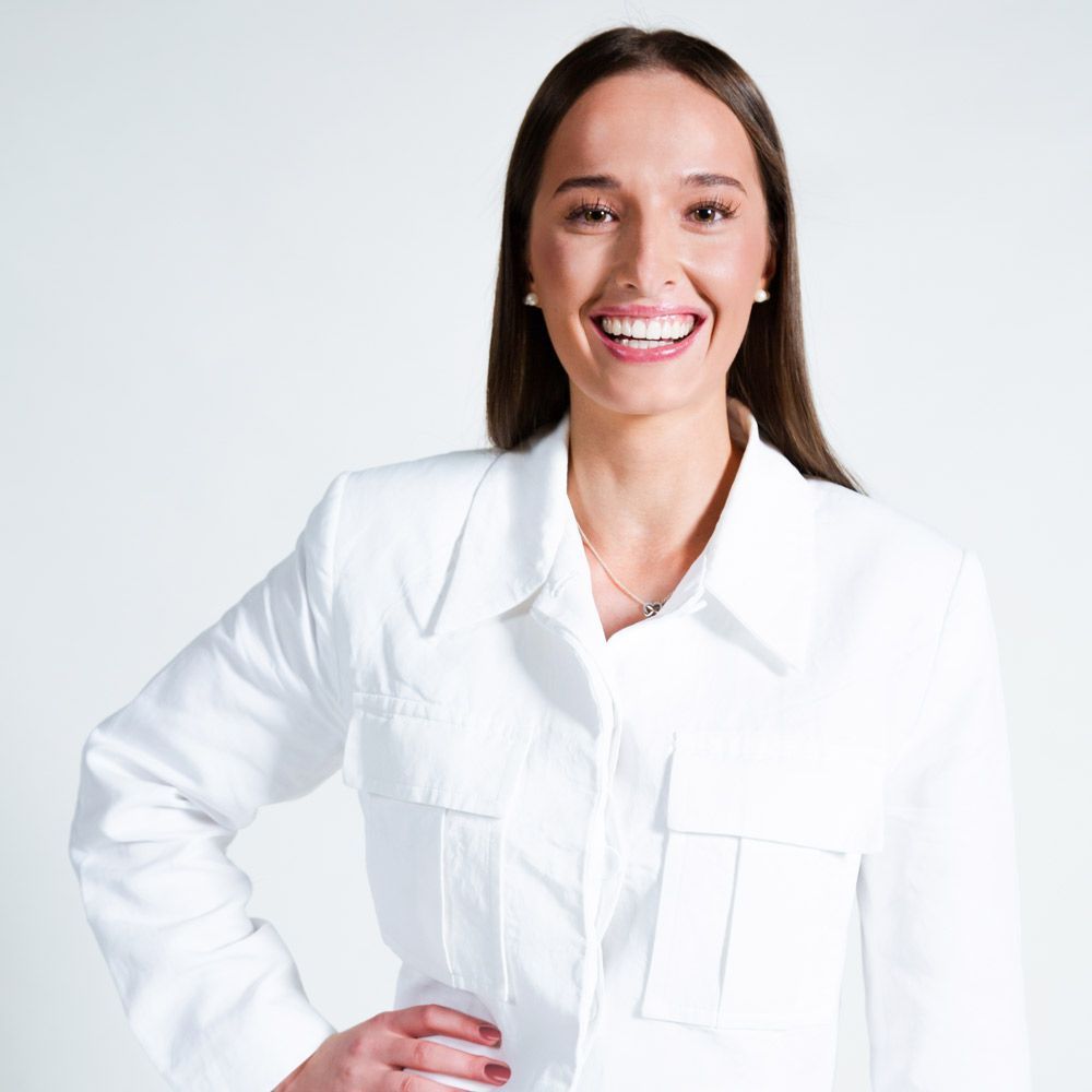 Eine Frau in einem hellbraunen Pullover lächelt und schaut in die Kamera