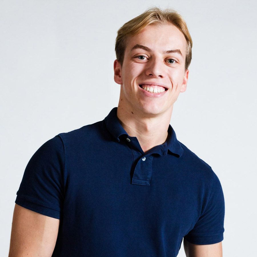 Ein junger Mann in einem gestreiften Hemd lächelt in die Kamera.