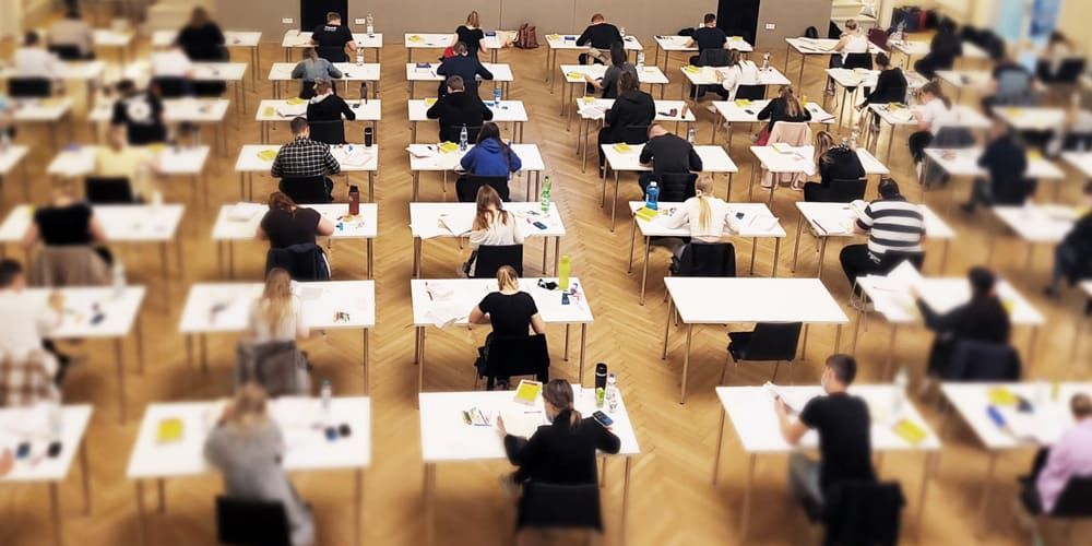 Eine große Gruppe von Menschen sitzt an Tischen in einem Klassenzimmer.