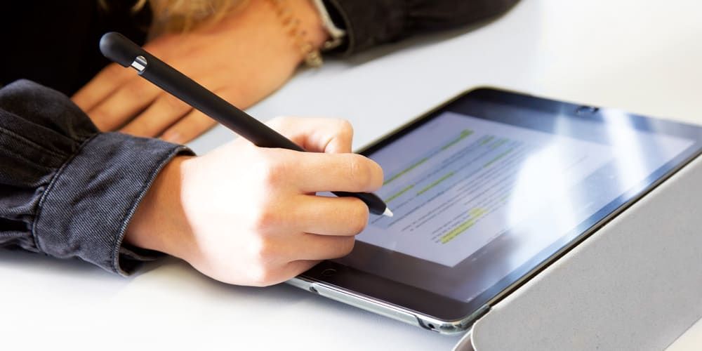Eine Person schreibt mit einem Stift auf einem Tablet.