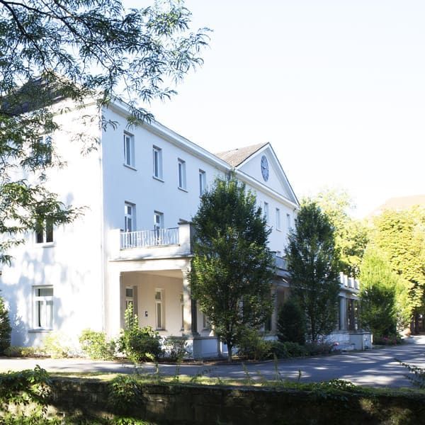 Ein großes weißes Gebäude mit Bäumen davor