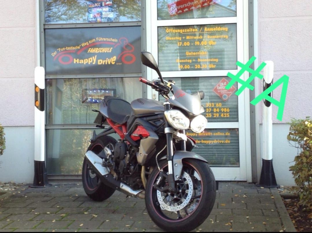 Ein Motorrad parkt vor einem Geschäft mit Glastüren. Die Türen befinden sich neben weißen Säulen.