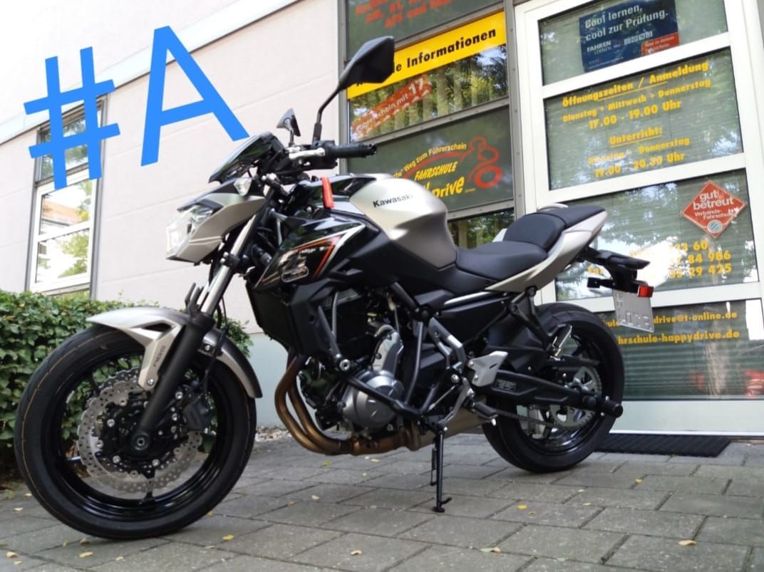 Ein Kawasaki-Motorrad mit schwarz-silberner Lackierung parkt vor einem Geschäft.