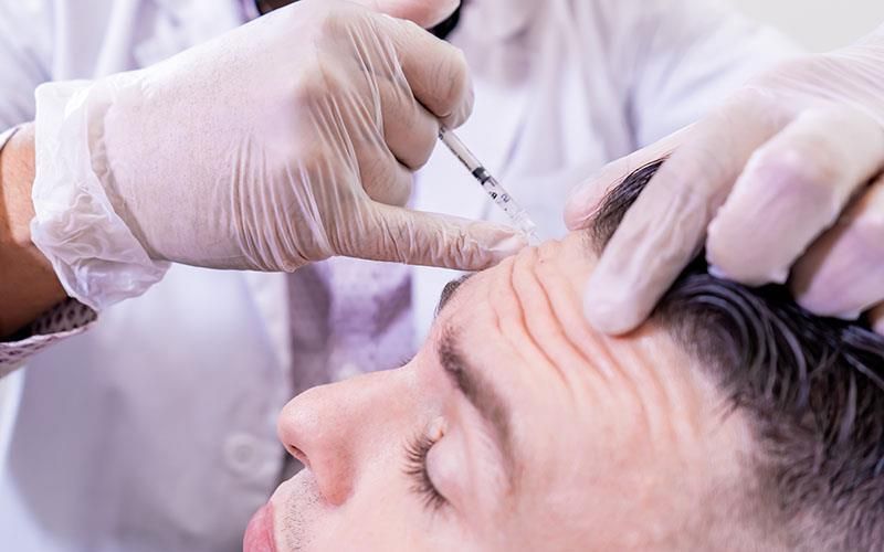 Ein Mann bekommt eine Botox-Injektion in die Stirn.