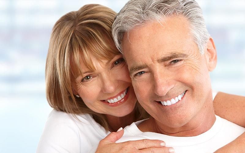 Ein Mann und eine Frau umarmen sich und lächeln in die Kamera.