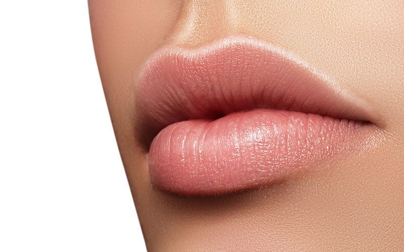 Eine Nahaufnahme der Lippen einer Frau mit rosa Lippenstift.