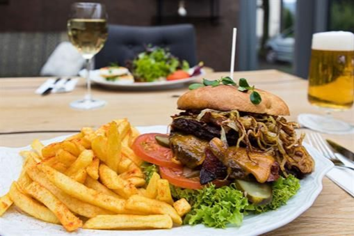 Ein Teller mit Essen, einem Hamburger und Pommes Frites auf einem Tisch.