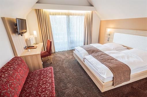 Ein Hotelzimmer mit Bett, Couch, Schreibtisch und Fernseher.