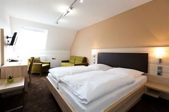 Ein Hotelzimmer mit Bett, Stuhl, Schreibtisch und Fernseher.