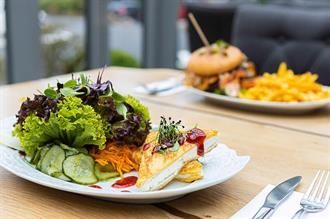 Ein Teller mit Essen, einem Salat und einem Sandwich auf einem Tisch.