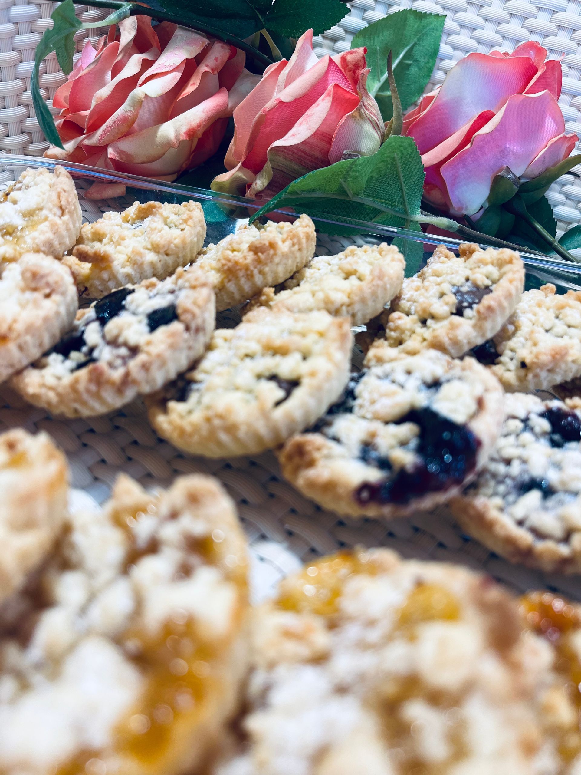 Primer plano de pasteles en un plato, con rosas rosas y melocotón en el fondo.
