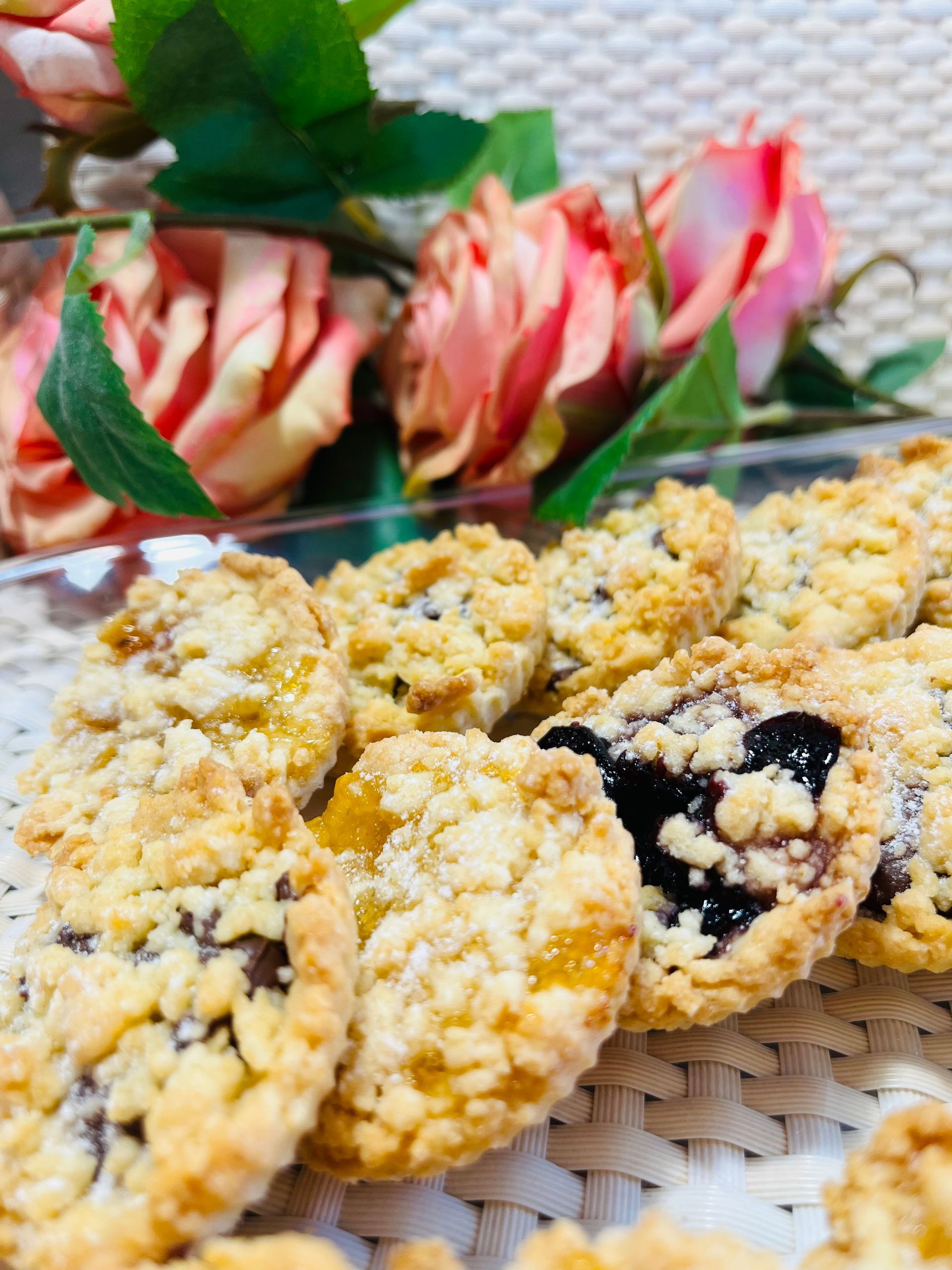 Galletas con relleno de frutas y cobertura de migas, primer plano con rosas rosas y naranjas.